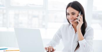 Woman smiling on the phone and using the computer