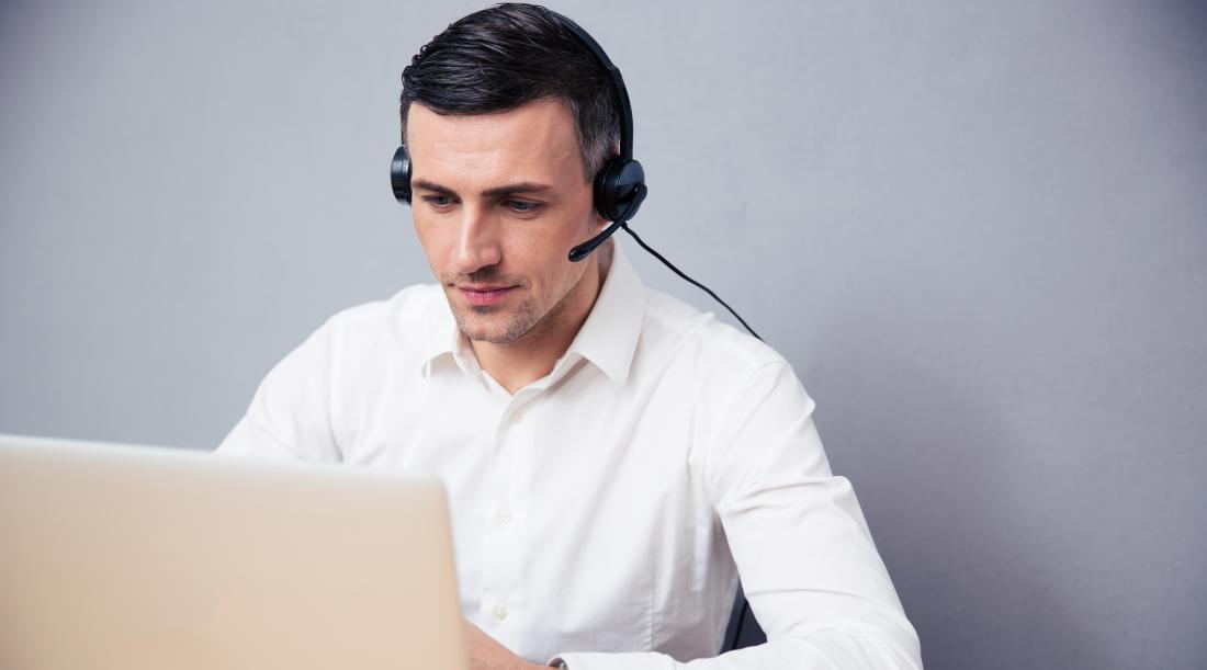 Man with a headset on sitting at a computer