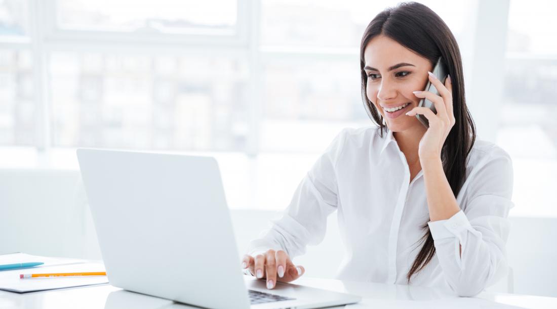 Woman smiling on the phone and using the computer