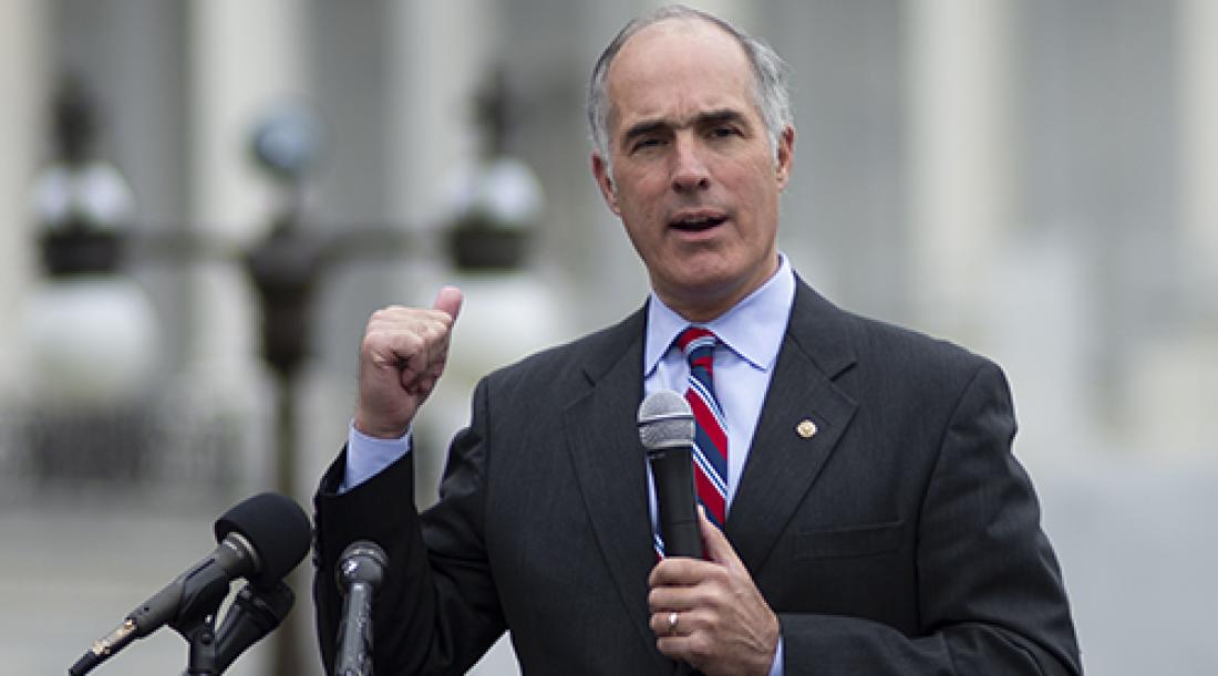Sen. Bob Casey speaking at a rally with his hand in a fist and a microphone.